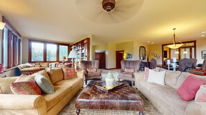 A spacious living room with leather sofas, a coffee table, and a bookshelf filled with books. - Butte View Chalet - Sleeps 10 (Crested Butte)