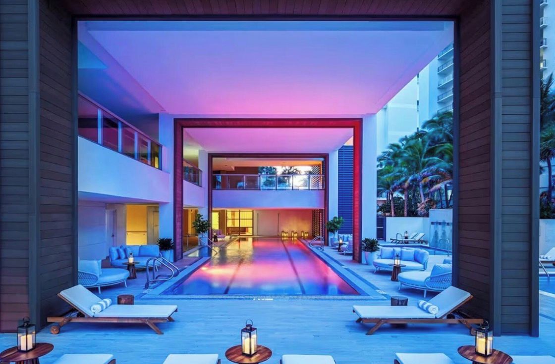 Un hotel moderno con piscina en la azotea, sillas de descanso y vistas de los edificios circundantes.
