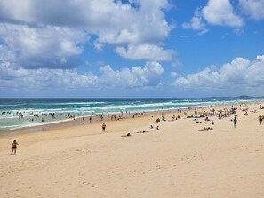 Uma praia com pessoas, tendas e guarda-sóis.