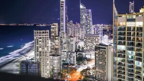A nighttime cityscape with high-rise buildings, a beach, and a view of the ocean. - Cozy Studio for 3 | 50m to Surfers Beach (Surfers Paradise)