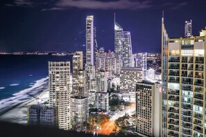 A nighttime cityscape with high-rise buildings, a beach, and a view of the ocean. - Cozy Studio for 3 | 50m to Surfers Beach (Surfers Paradise)