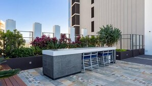An outdoor bar area with a stone countertop, seating, and plants. - Cozy Studio for 3 | 50m to Surfers Beach (Surfers Paradise)