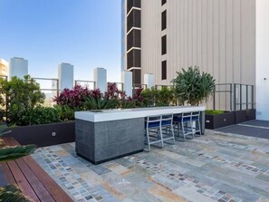 An outdoor bar area with a stone countertop, seating, and plants. - Cozy Studio for 3 | 50m to Surfers Beach (Surfers Paradise)