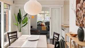 En matplats med ett bord dukat för två personer, en hängande lampa och utsikt över vardagsrummet.