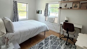 Une chambre à coucher comprenant un lit, une table de chevet, une chaise, un bureau et une fenêtre.