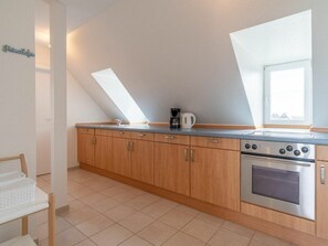 A kitchen with wooden cabinets, a stainless steel stove, and a skylight. - 54-degree Panoramic View (St. Peter-Ording)