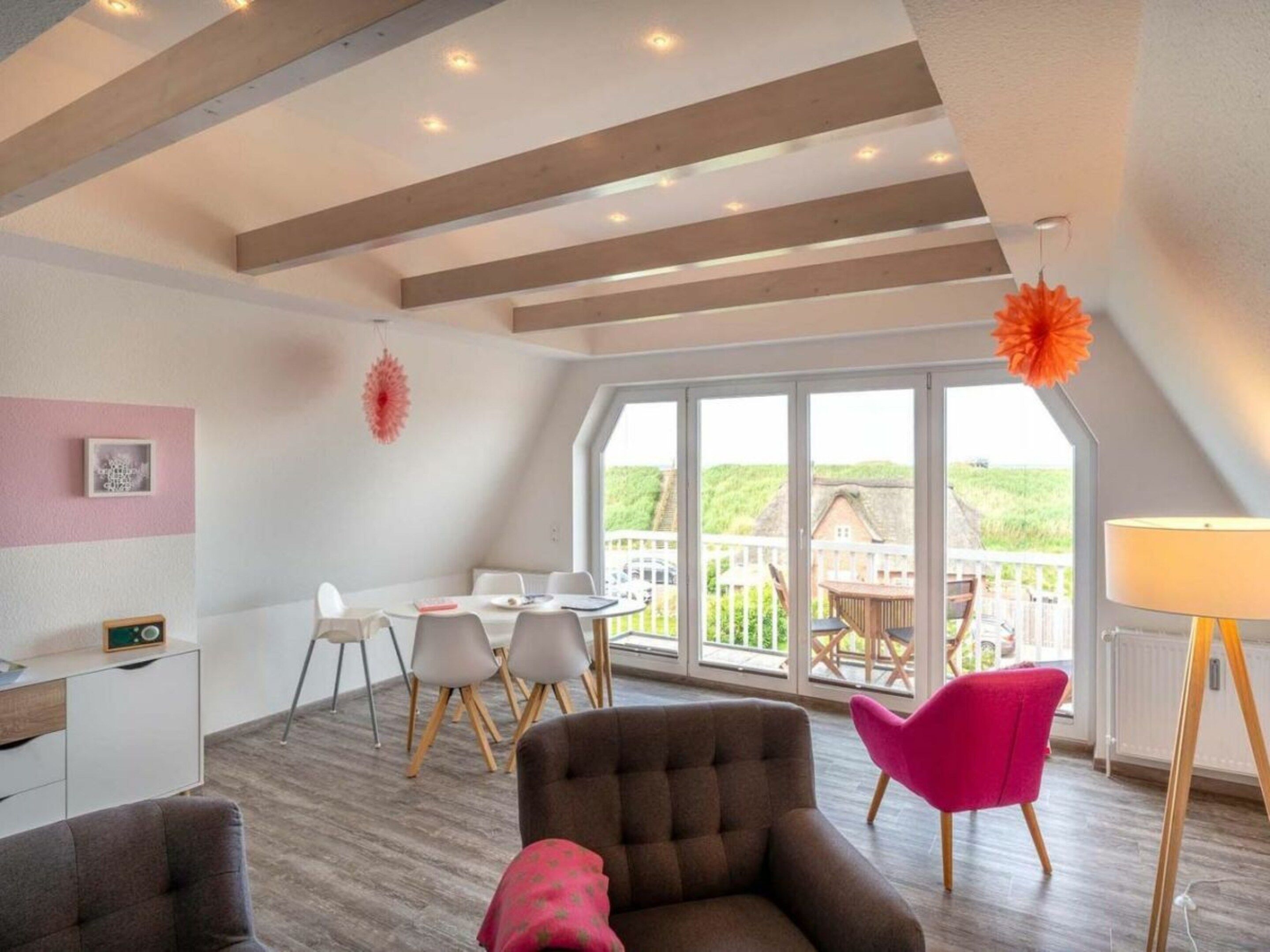 Ein modernes Interieur mit Essbereich, einer Couch und einem großen Fenster mit Blick ins Freie.