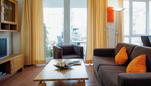 A living room with a sofa, armchair, coffee table, and a television. - Holiday Apartment With 1 Bedroom (Grossenbrode)