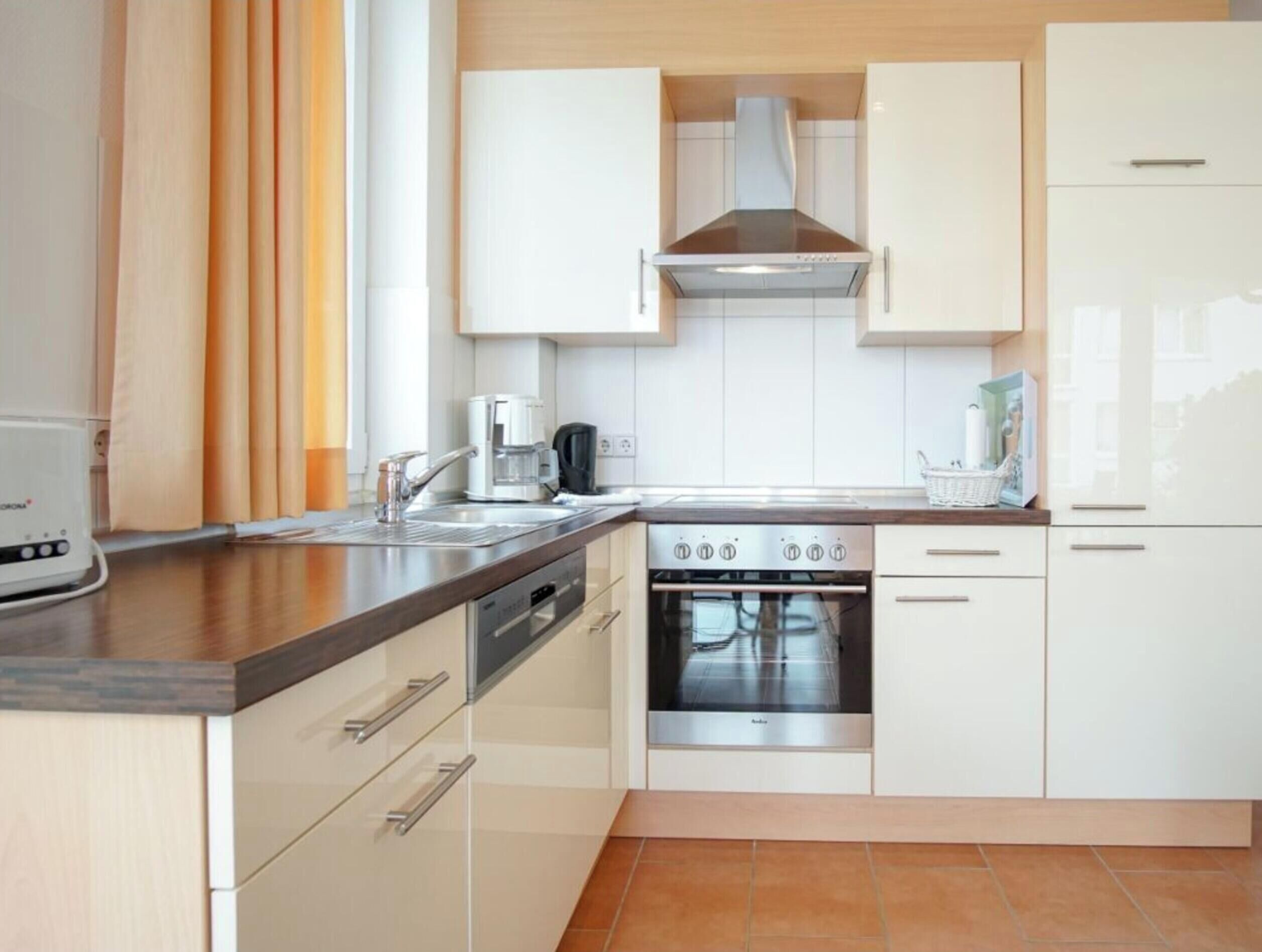 A modern kitchen with white cabinetry, a stainless steel range, and a coffee maker.