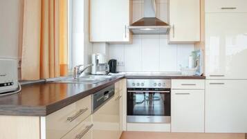 A modern kitchen with white cabinetry, a stainless steel range, and a coffee maker.