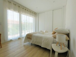 A bedroom with a bed, bedside table, and a window with curtains. - Aroeira Nest | 3-Bedroom Villa with Pool and BBQ (Almada)