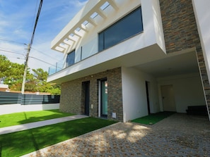 A modern two-story house with a flat roof, large windows, and a stone facade. - Aroeira Nest | 3-Bedroom Villa with Pool and BBQ (Almada)
