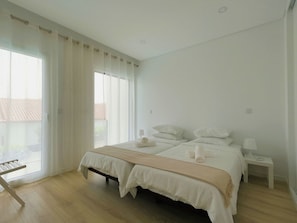 A bedroom with a large bed, bedside tables, and a window with curtains. - Aroeira Nest | 3-Bedroom Villa with Pool and BBQ (Almada)