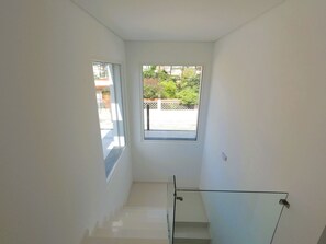 A staircase leading to a balcony with a view of greenery and a fence. - Aroeira Nest | 3-Bedroom Villa with Pool and BBQ (Almada)