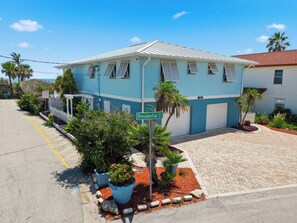 A two-story building with a blue and white facade, a covered porch, and a paved driveway. - 5BR Beachfront Escape | Private Beach Access (Cape Canaveral)