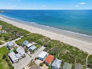 Ein Küstenwohngebiet mit Häusern direkt am Strand, einem Sandstrand und freiem Blick auf das Meer.