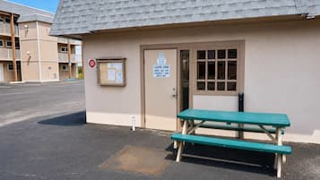 Un petit bâtiment avec une enseigne indiquant une buanderie, un banc et un panneau interdisant le stationnement.