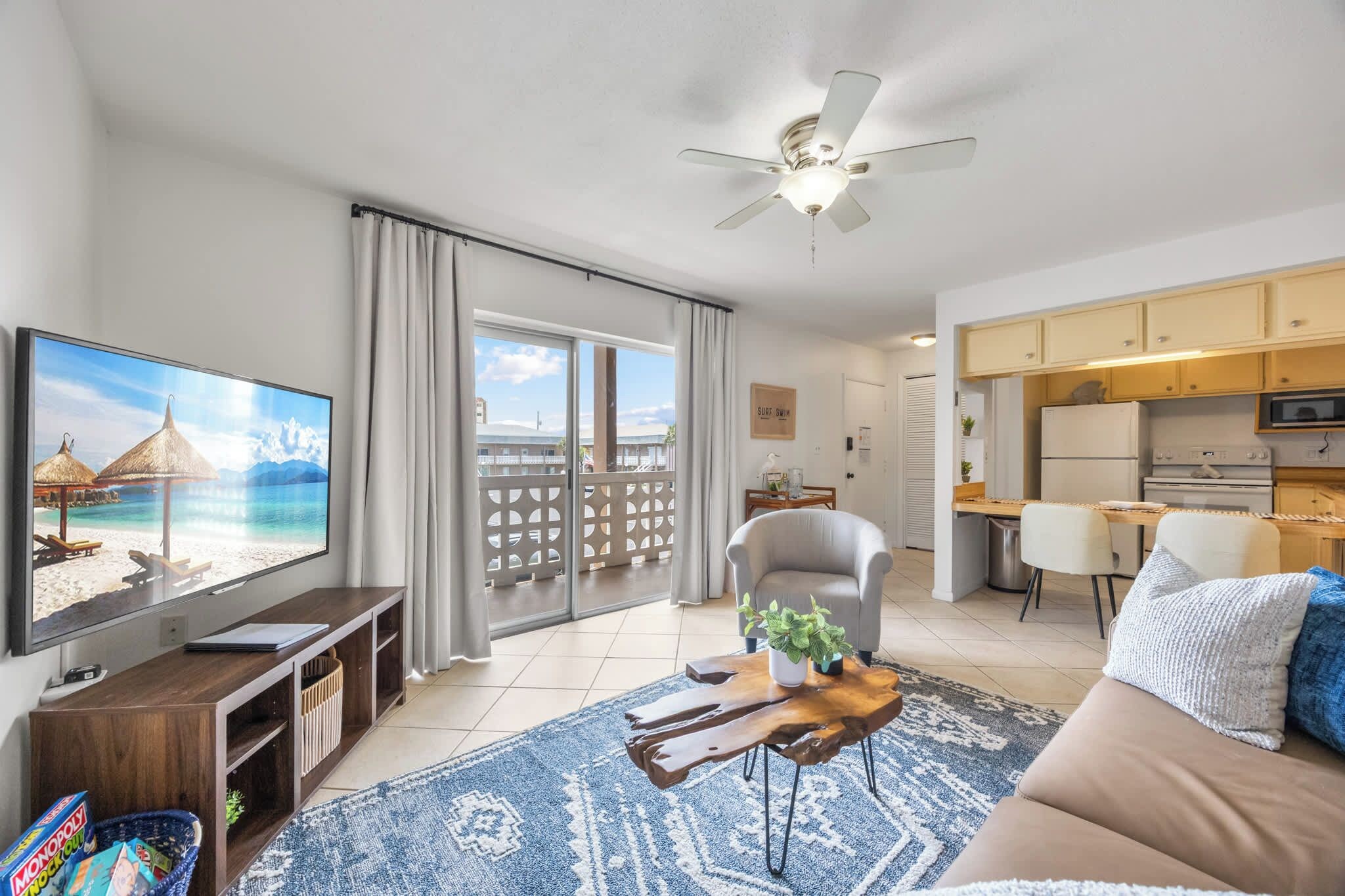 A living room with a television, sofa, coffee table, and a view of the balcony.