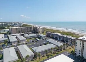 A coastal hotel complex with multiple buildings, parking areas, and a beach view. - The Diplomat 2BR with Pool and Beach Access (Cocoa Beach)