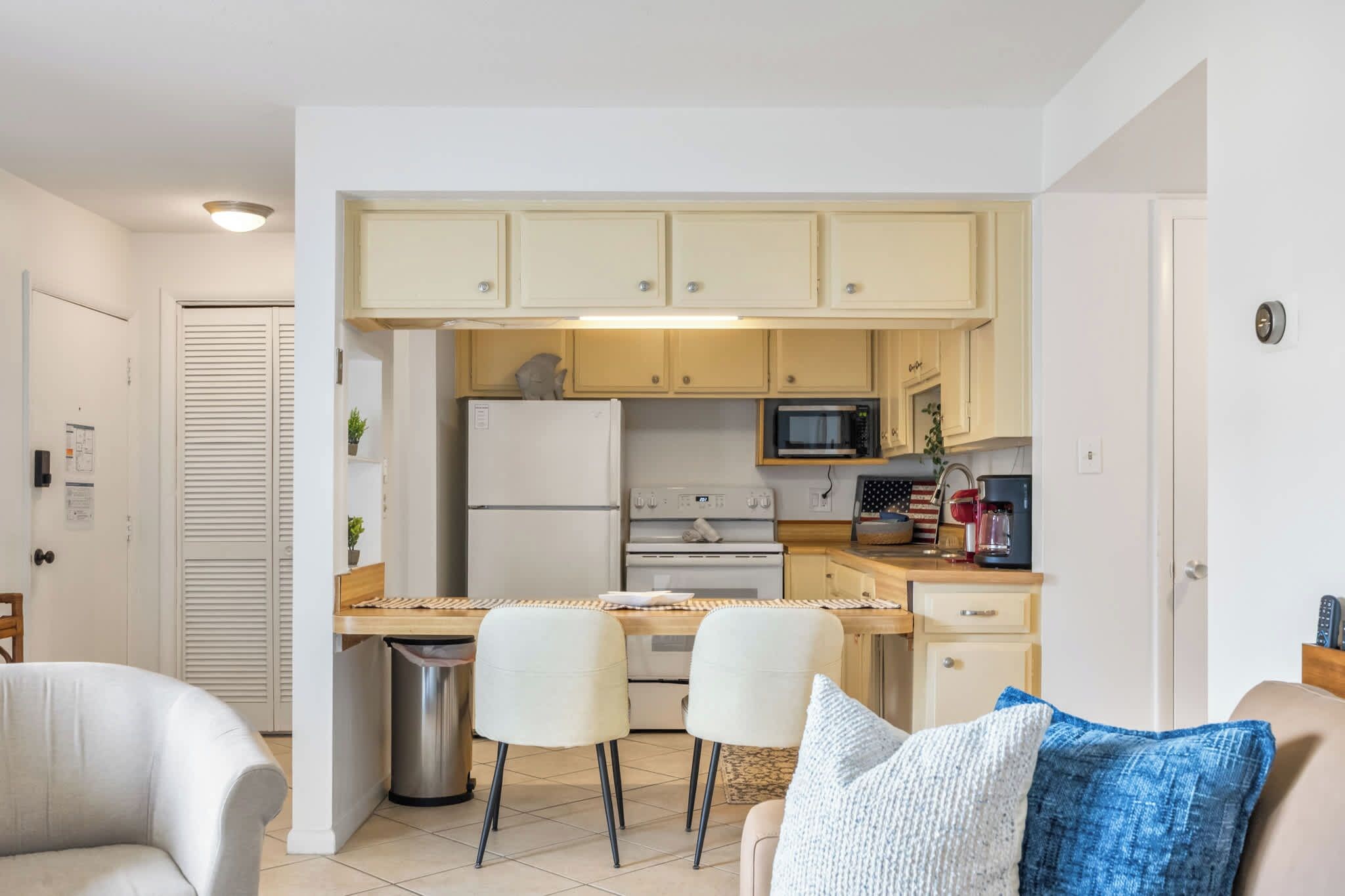Une cuisine compacte équipée d’un four à micro-ondes, d’un four et d’un réfrigérateur. Elle comprend également un coin repas avec deux chaises et une petite table.