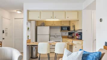 Une cuisine compacte équipée d’un four à micro-ondes, d’un four et d’un réfrigérateur. Elle comprend également un coin repas avec deux chaises et une petite table.