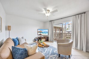 A living room with a sofa, armchair, coffee table, and a ceiling fan. - The Diplomat 2BR with Pool and Beach Access (Cocoa Beach)
