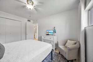 Une chambre à coucher avec un lit, une commode, un téléviseur et une chaise.