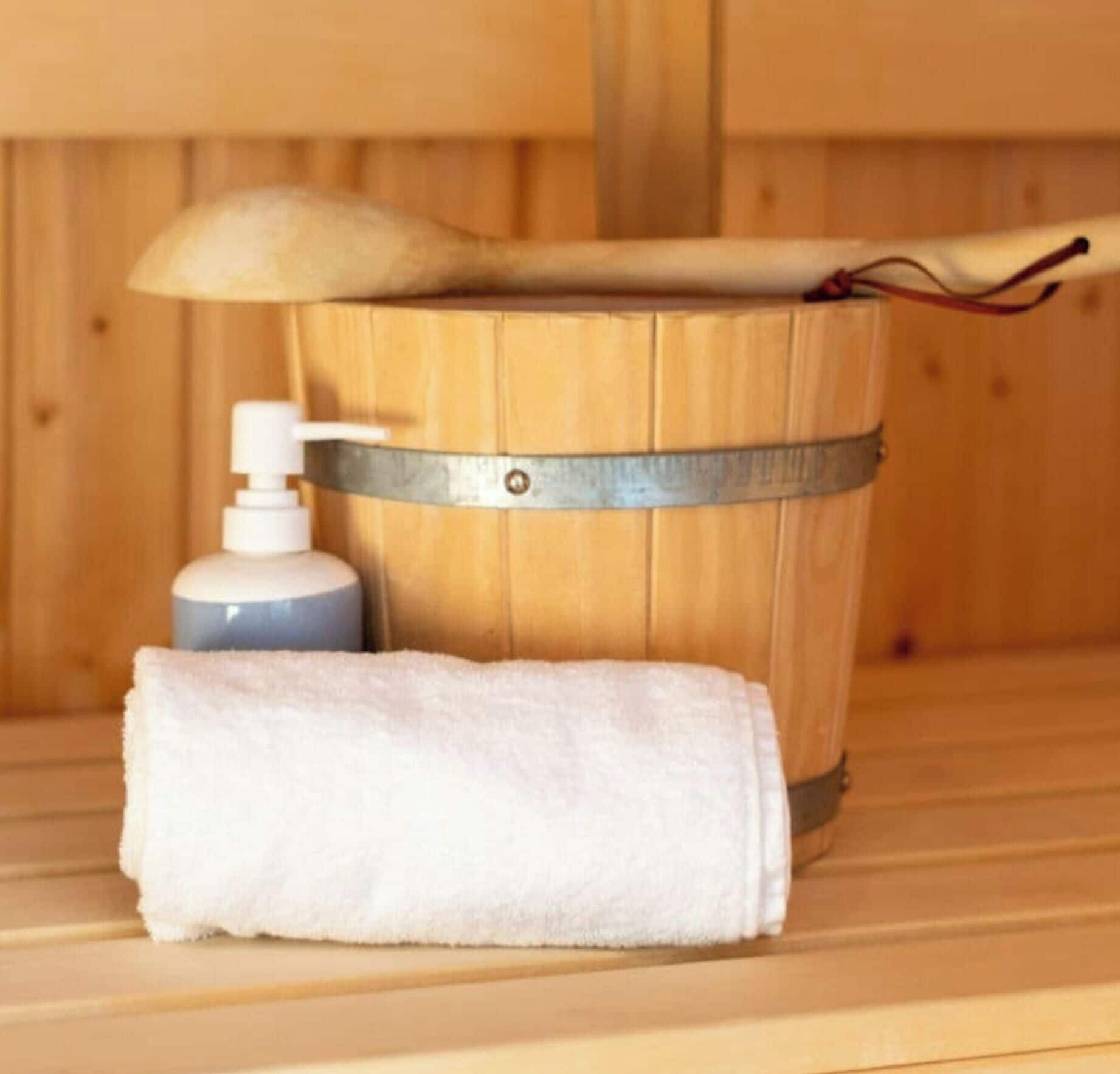 A wooden sauna with a towel and a bottle of soap.