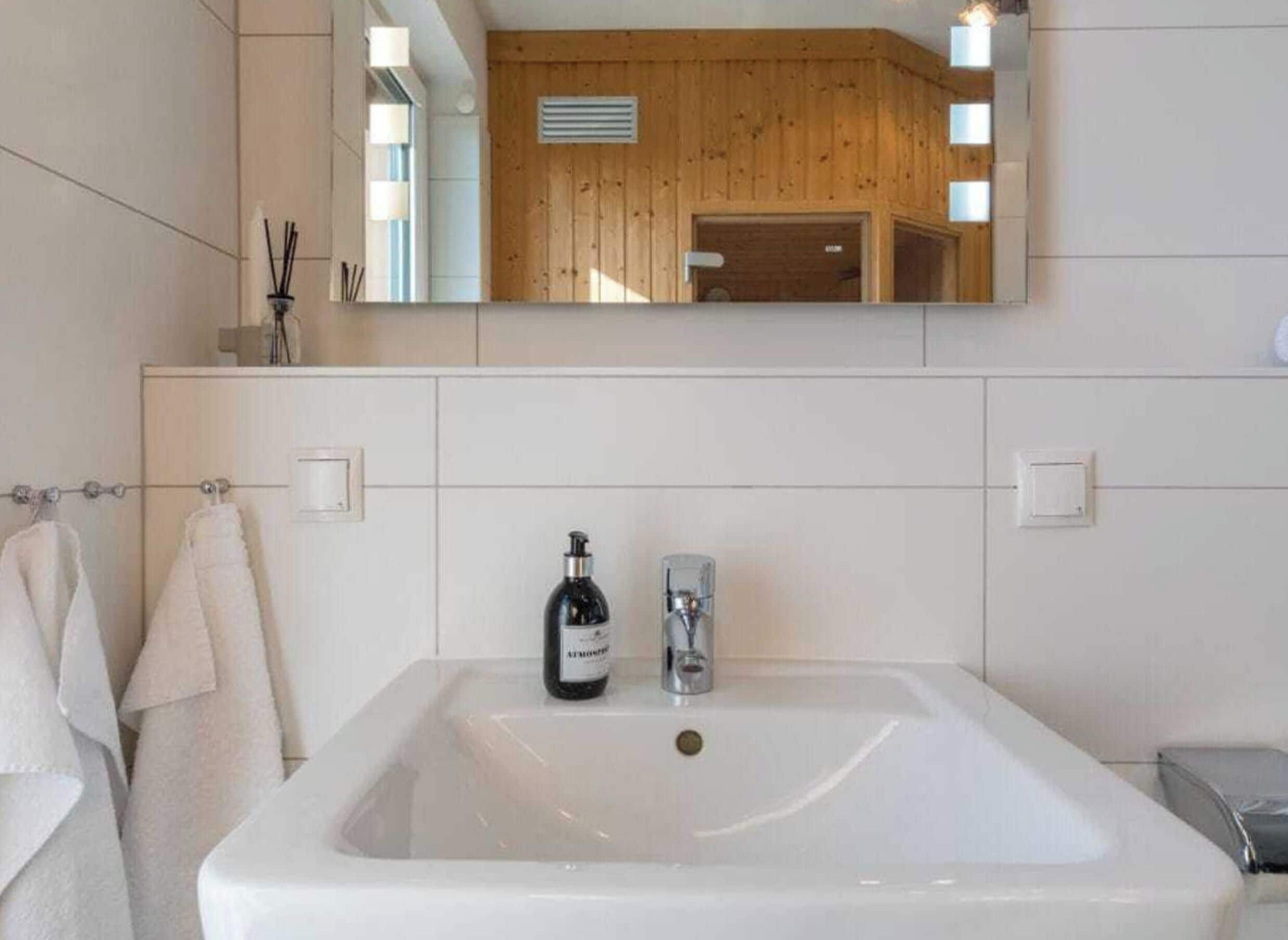 Un baño con un lavamanos grande de color blanco, un espejo y una pared revestida de paneles de madera.