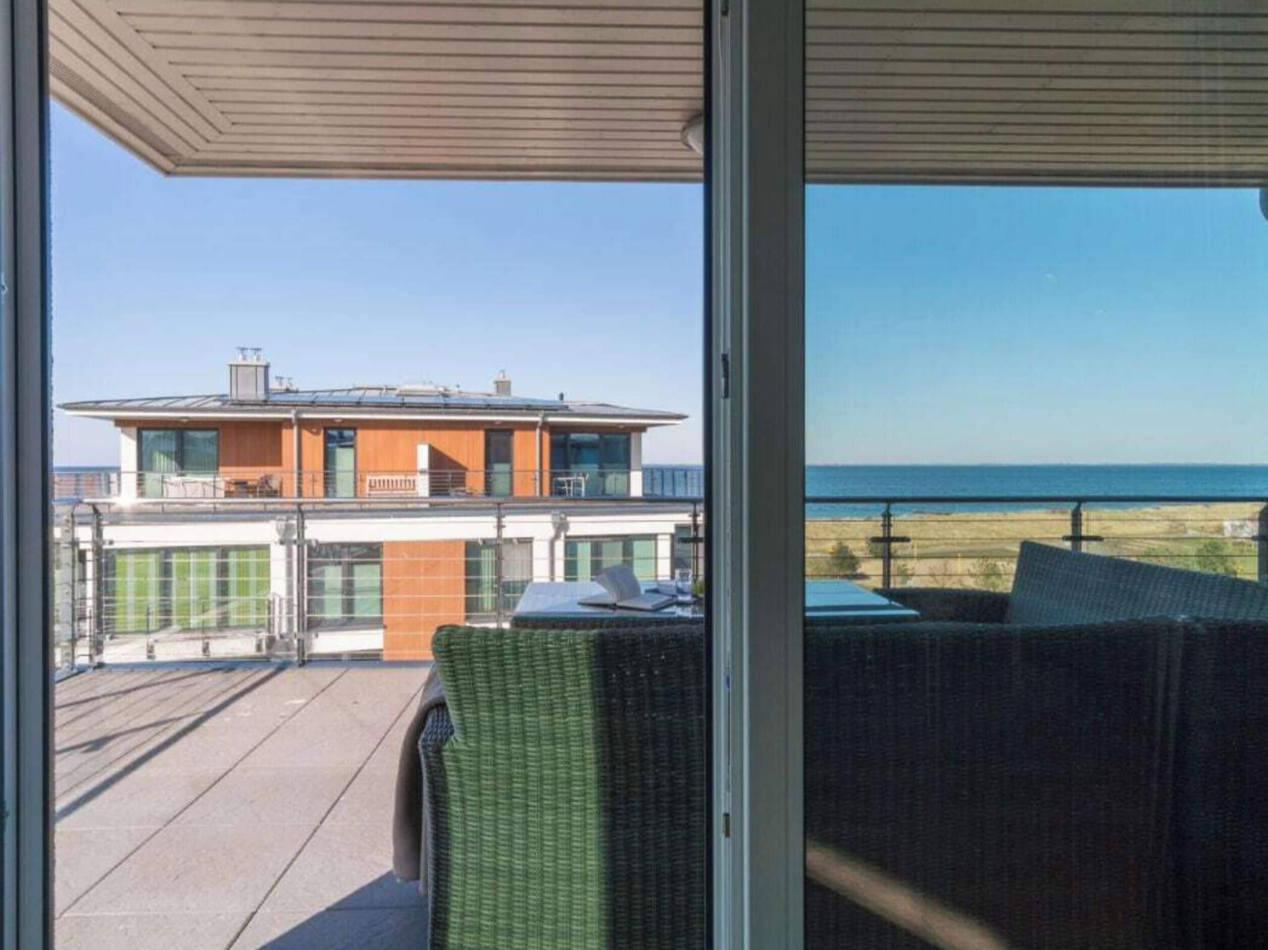 Ein Balkon mit Blick auf ein modernes Gebäude und das Meer.