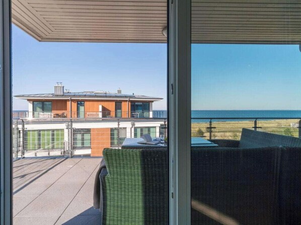 A balcony with a view of a modern building and the ocean.
