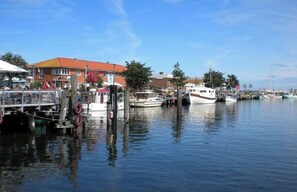 A marina with boats docked, a building with a red roof, and a clear blue sky.