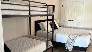 Ein Zimmer mit Etagenbetten, einem Deckenventilator, einer Tür und einem gefliesten Boden.