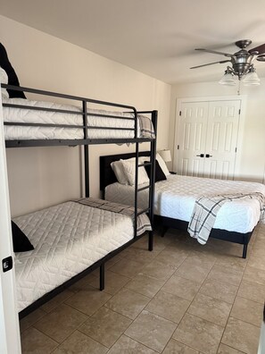 A room with bunk beds, a ceiling fan, a door, and a tiled floor. - Charming lake front 2-bedroom cottage with AC on peaceful Lake Eufaula, OK. (Canadian)