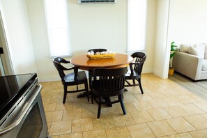 A dining area with a round table, four chairs, and a bowl of fruit.