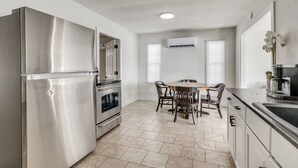 Eine moderne Küche mit Edelstahlgeräten, ein Essbereich mit Tisch und Stühlen sowie ein Fenster mit Jalousien.