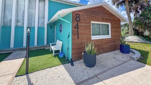 A house with a number 841 on the side, a white bench, and a potted plant. - A-Wave From It All #1 - Pet-Friendly Pool Home (New Smyrna Beach)
