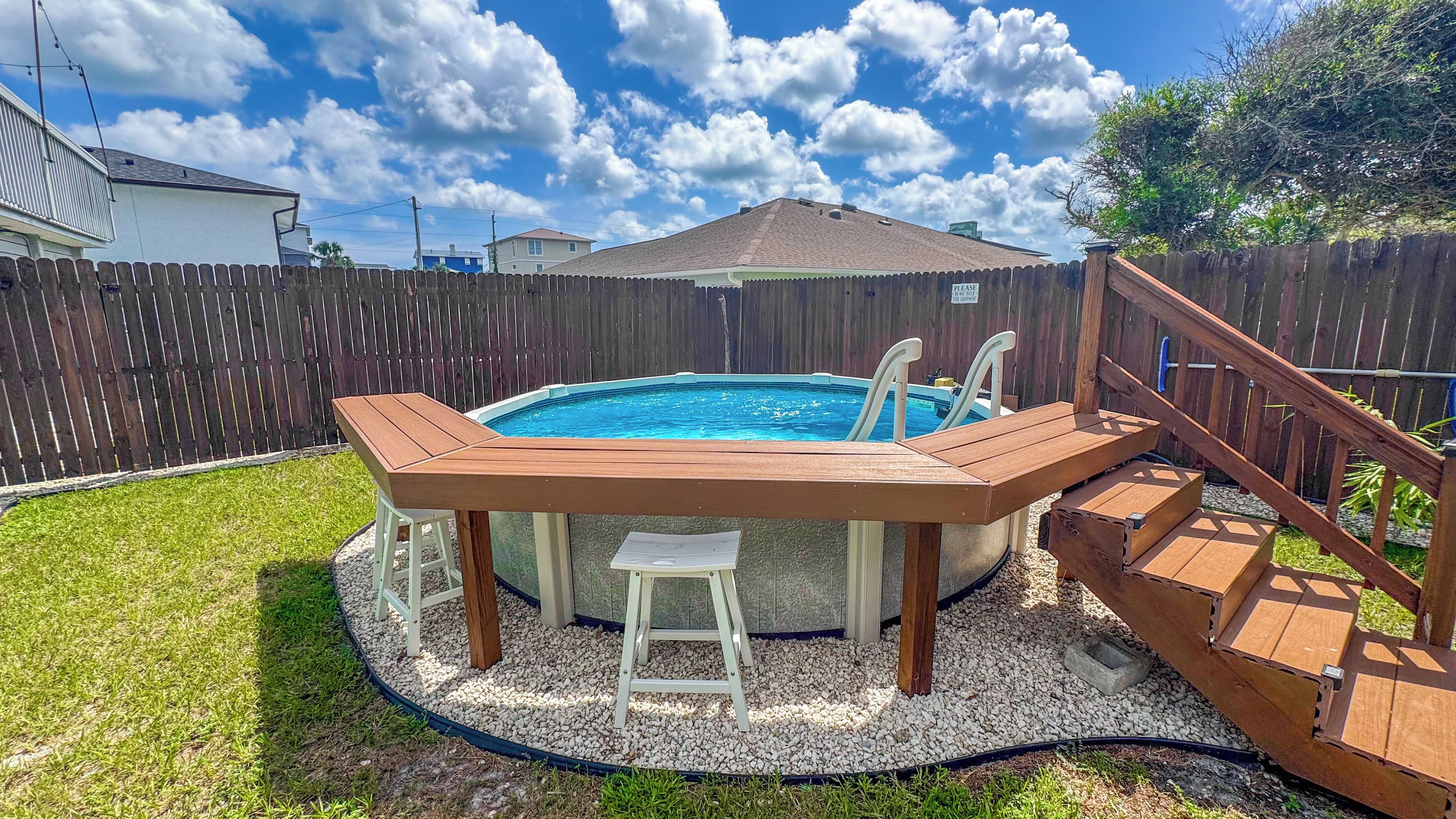 Ein Garten mit Whirlpool, Holzterrasse und umzäunter Fläche.