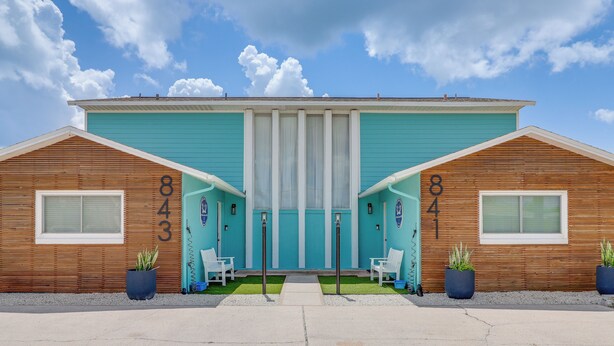 Un immeuble de deux étages à la façade turquoise, portant les numéros 843 et 841, avec une entrée centrale, une porte et deux fenêtres de chaque côté.