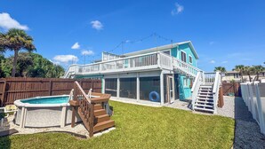 Une maison à deux étages avec une piscine, une terrasse et une cour gazonnée.