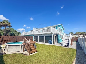 Une maison à deux étages avec une piscine, une terrasse et une cour gazonnée.