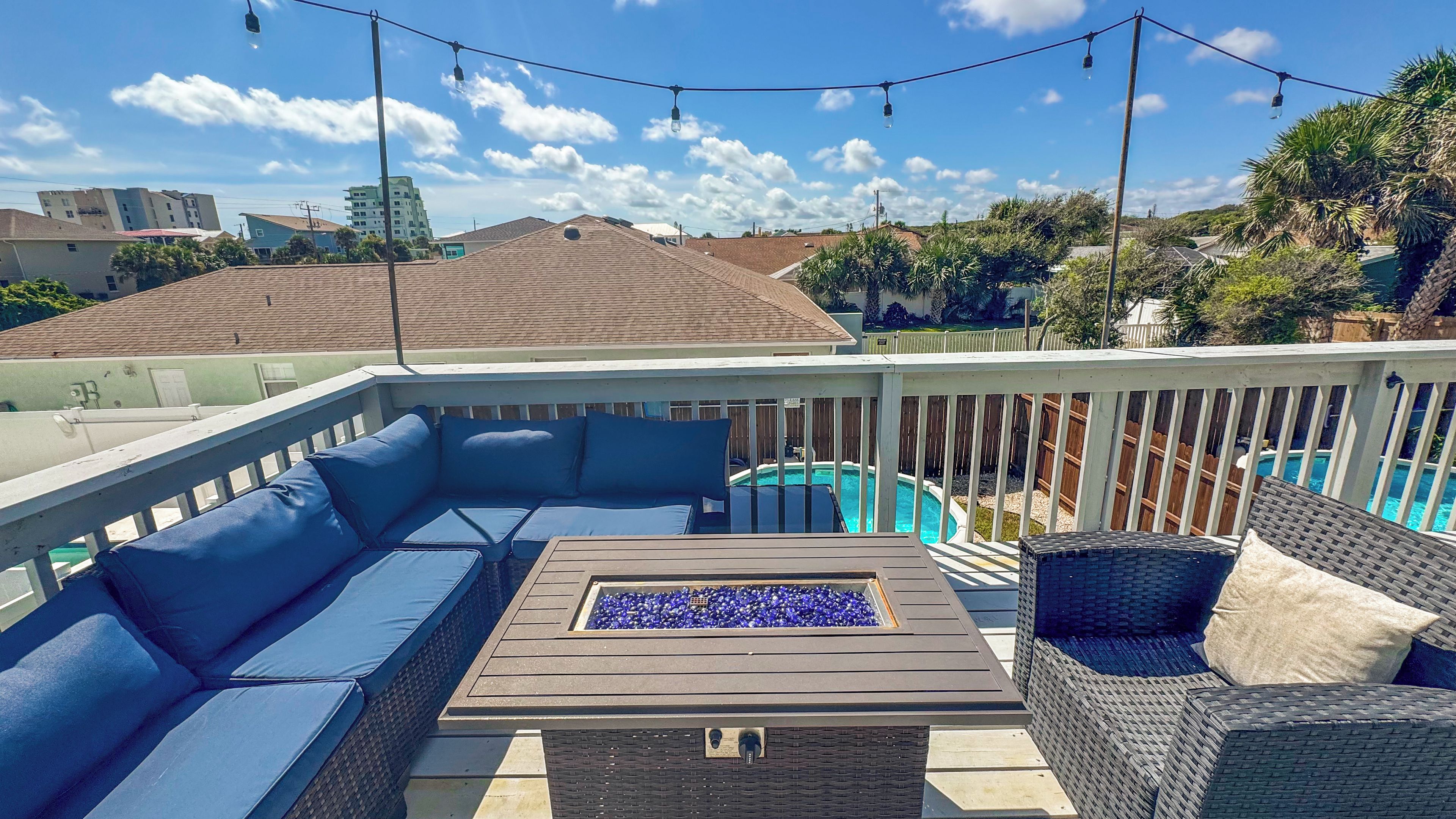 A rooftop deck with a pool, outdoor furniture, and string lights.