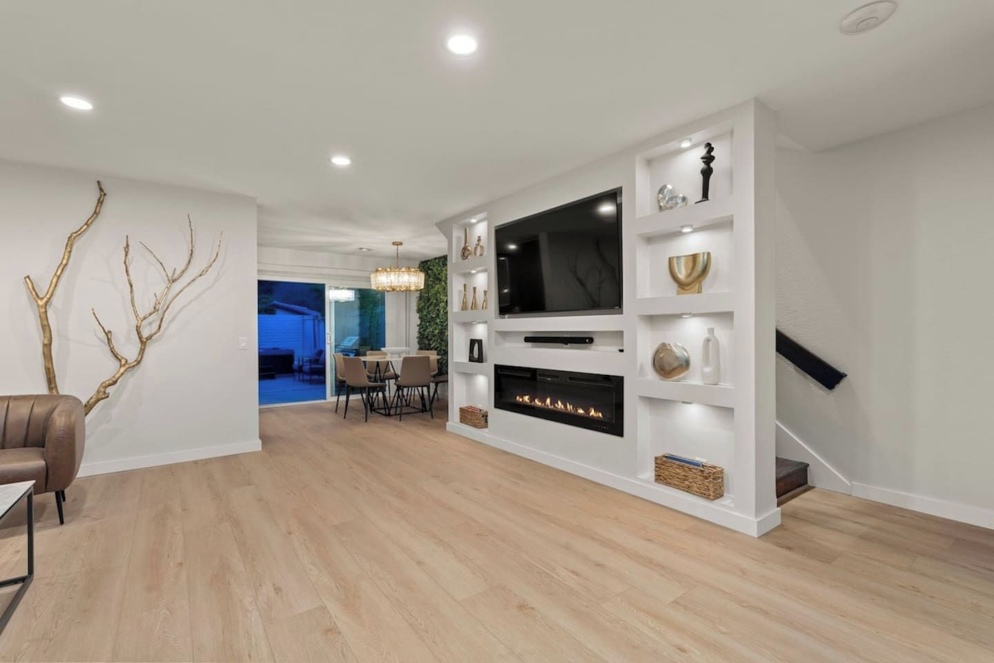 Una sala de estar moderna con televisor de pantalla plana, chimenea y comedor con sillas y una mesa.