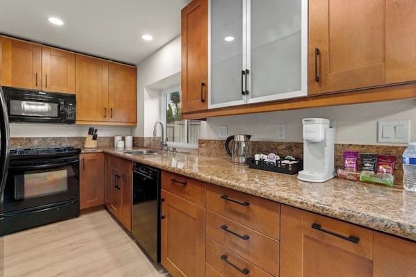 A modern kitchen with wooden cabinets, a stainless steel refrigerator, a microwave, a coffee maker, and a dishwasher.