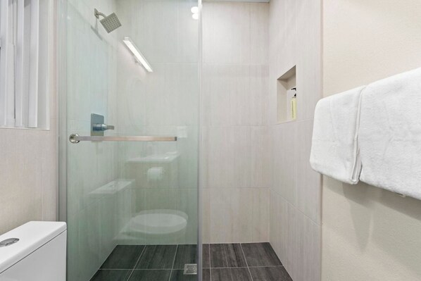 Un baño moderno con cabina de ducha de vidrio, un inodoro y un perchero para toallas.