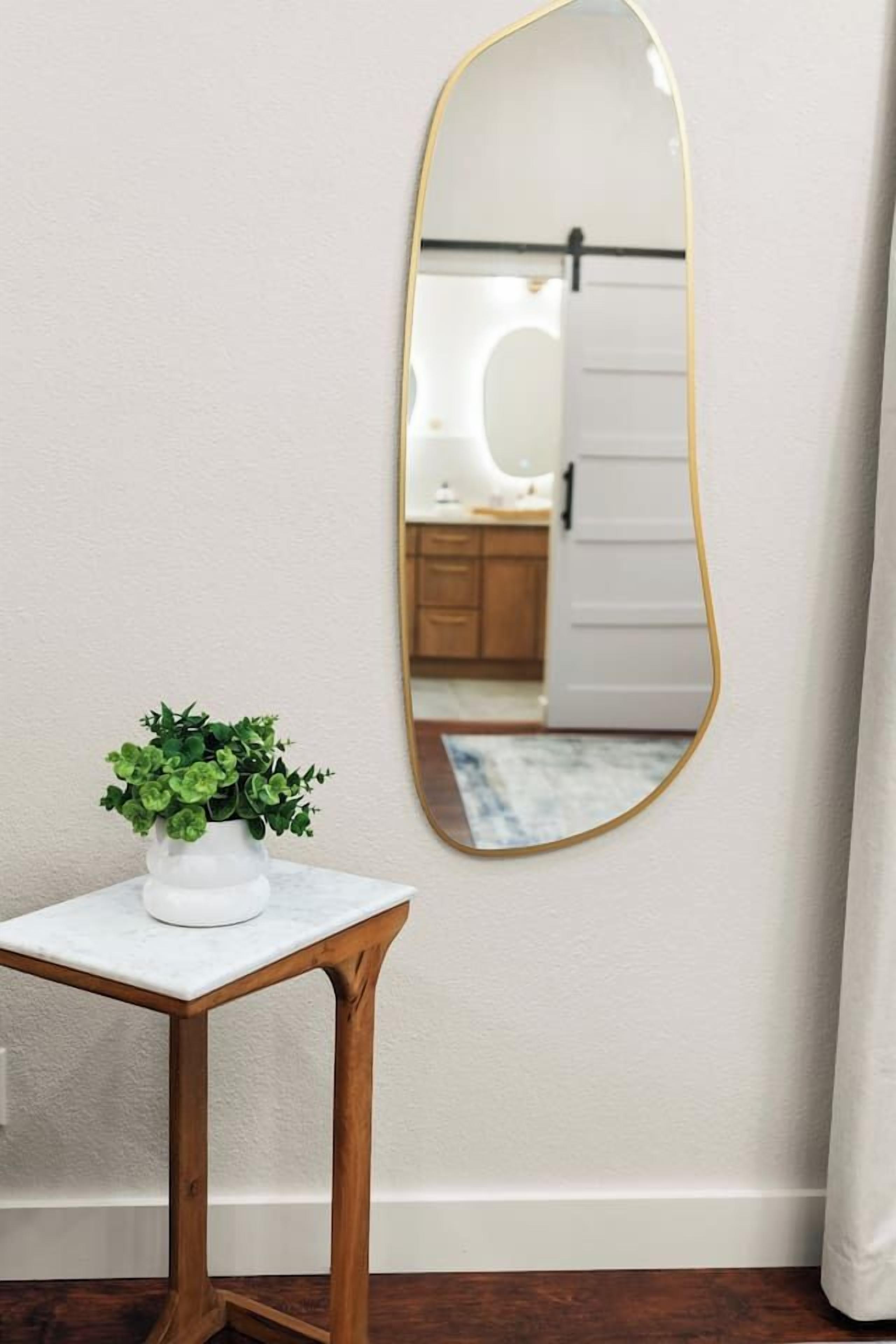 A room with a white marble table, a potted plant, and a mirror with a gold frame.