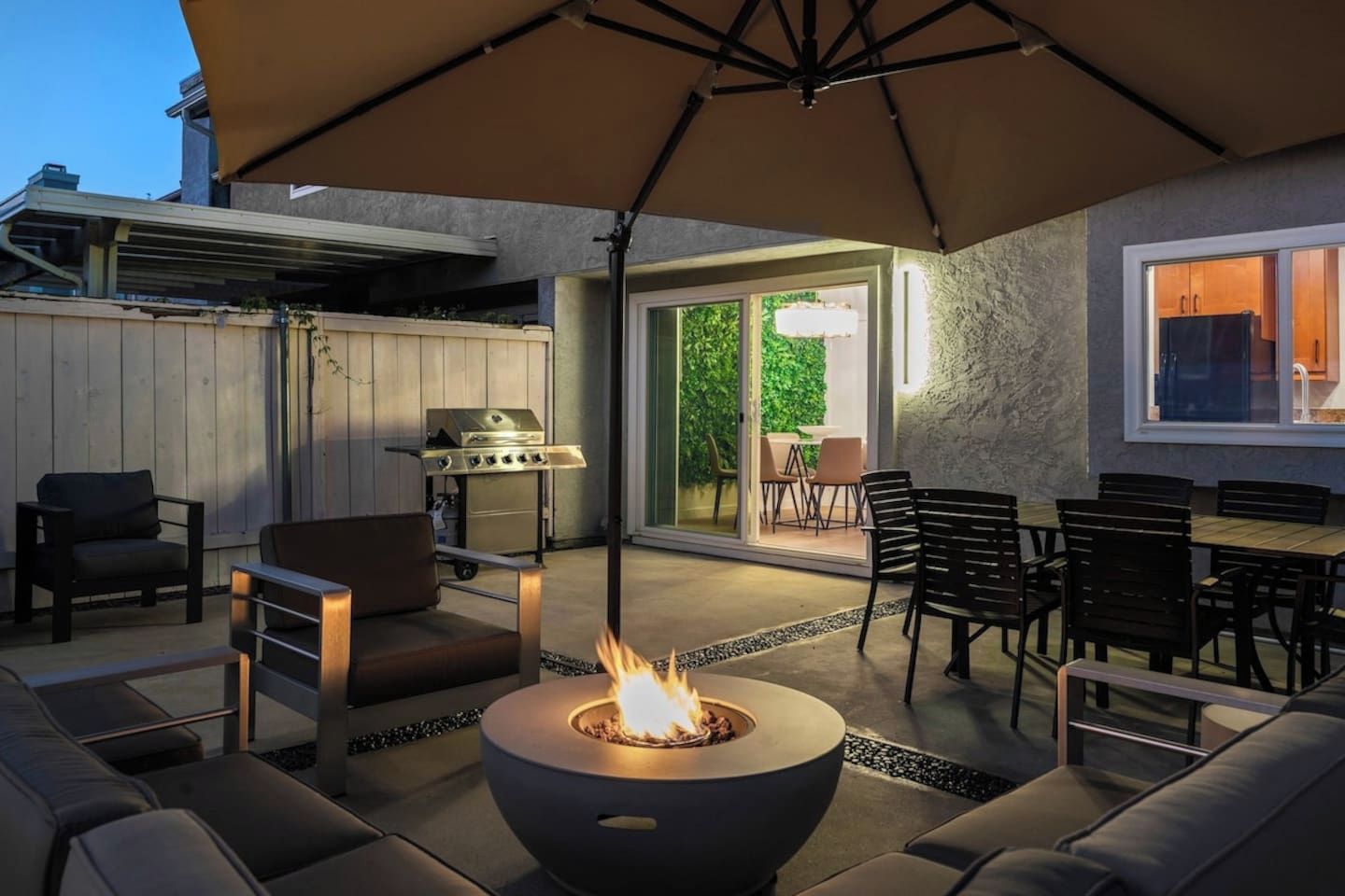 An outdoor patio with a fire pit, seating, and a grill.