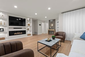 A modern living room with a fireplace, a flat-screen TV, and a comfortable seating area.