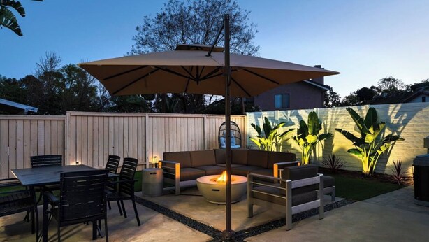 Ein Außenbereich mit Terrasse, Tisch, Stühlen, einer Couch und einem Feuerkorb.