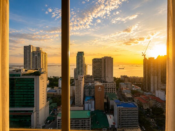 A cityscape with high-rise buildings, a body of water, and a sunset.